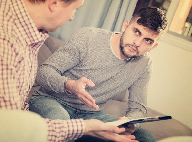 男人在家里的沙发上和朋友焦急地讨论文件图片下载