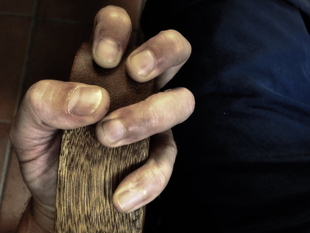 一只紧张的手紧抓着椅子的木扶手图片下载