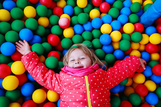 小女孩在满是五颜六色的球的池子里玩图片下载