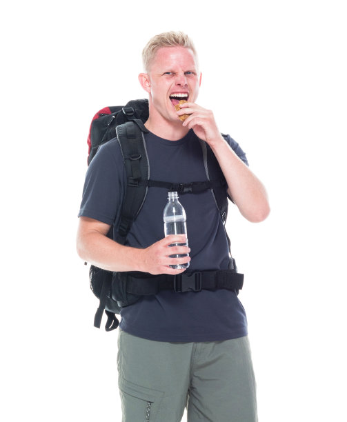 迷人的年轻男性徒步旅行者吃和喝零食图片下载