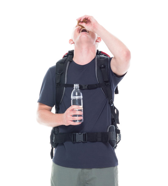 迷人的年轻男性徒步旅行者吃和喝零食图片下载