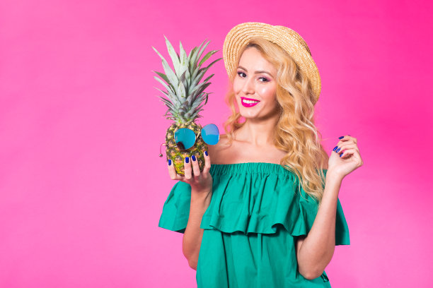 时尚肖像年轻美丽的女人与菠萝在粉红色的背景与copyspace图片下载