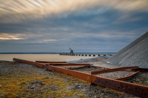 长曝光照片的钢铁垃圾在前景和一个老起重机在一个码头在背景图片下载