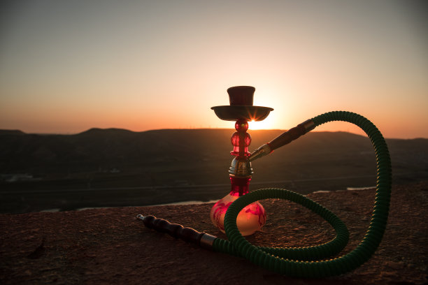 水烟，传统阿拉伯水管，直接日落光，户外照片。山的背景或水烟的剪影在日落的背景。户外。图片下载