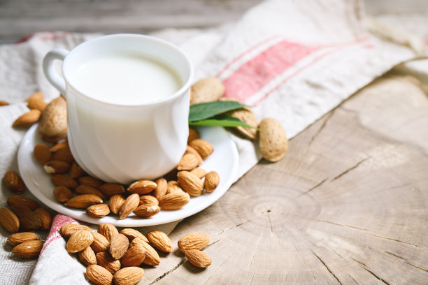 夏日花园的木桌上放着杏仁和杏仁牛奶。有用的食物图片下载