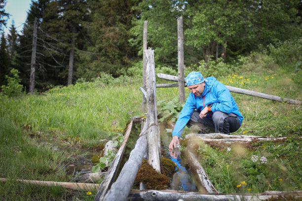 徒步旅行者从森林的小溪中取水图片下载