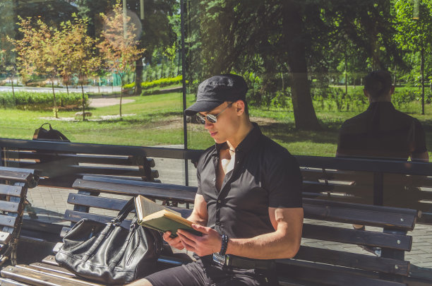 一个穿衬衫戴眼镜的学生在城市公园看书图片下载