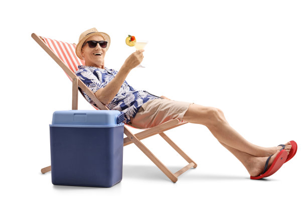 年长的游客拿着鸡尾酒坐在甲板上的椅子上，旁边是一个冷却箱图片下载