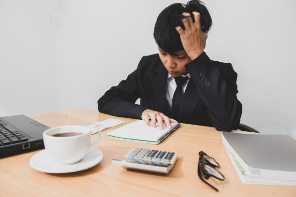 亚洲年轻人在黑色西装是压力担心问题工作坐在办公室的椅子上。图片下载