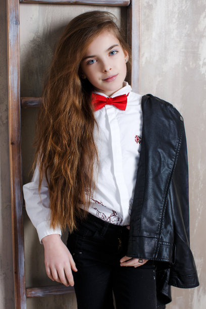 一个穿着白色衬衫打着领结，背景是灰色的女孩的工作室肖像图片下载