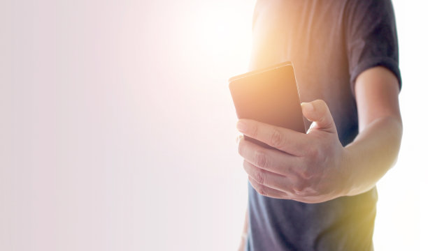 一名男子用手拿着带爆光的智能手机图片下载