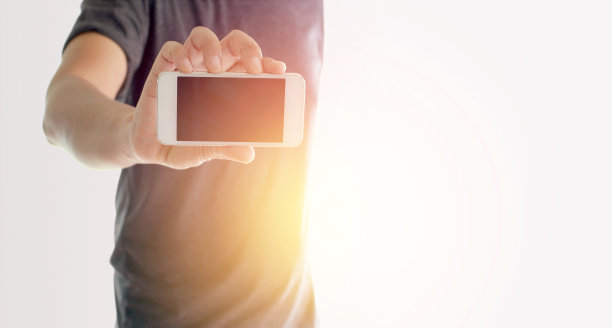 一名男子用手拿着带爆光的智能手机图片下载