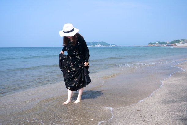 年轻女子走在潮湿的沙滩上图片下载