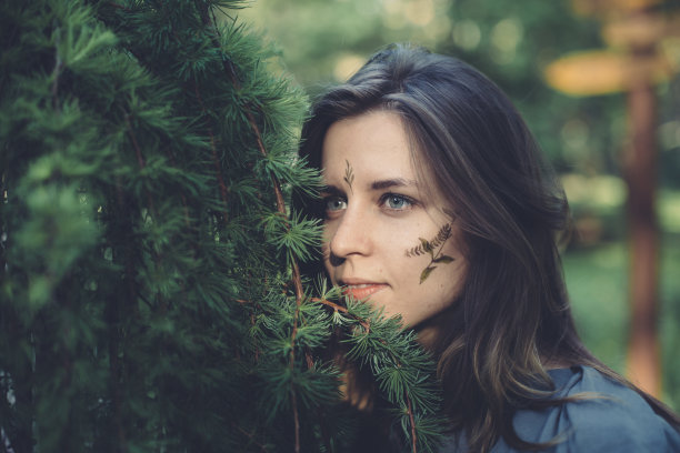 一个年轻女孩的肖像与树叶和植物标本室室外旁边的一棵树图片下载