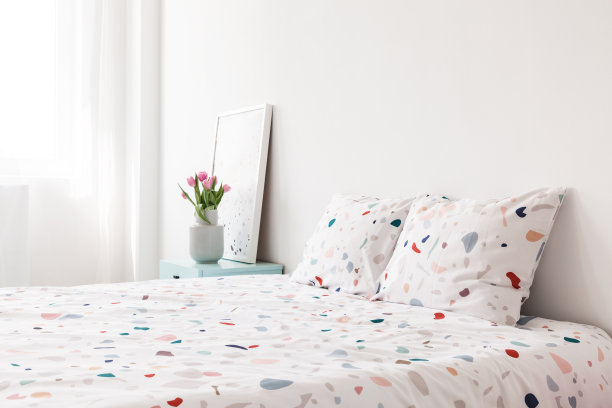 带有图案的床单和床垫在明亮的卧室里，里面有鲜花。真实的照片图片下载