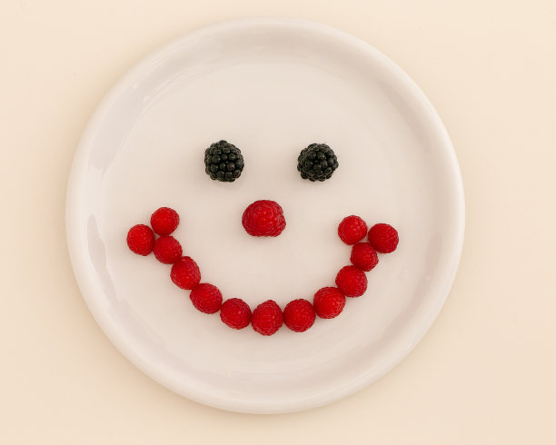 新鲜、成熟的覆盆子和黑莓放在白色的盘子上。白色背景图片下载