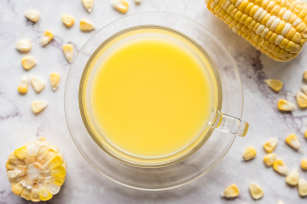 大理石桌上放着一杯玉米牛奶和新鲜的甜玉米。俯视图图片下载