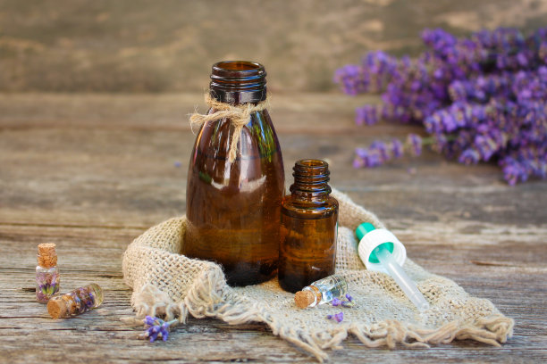 薰衣草油在不同的瓶子在木制背景。图片下载