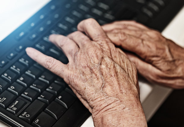 年长妇女的手在电脑键盘上打字图片下载