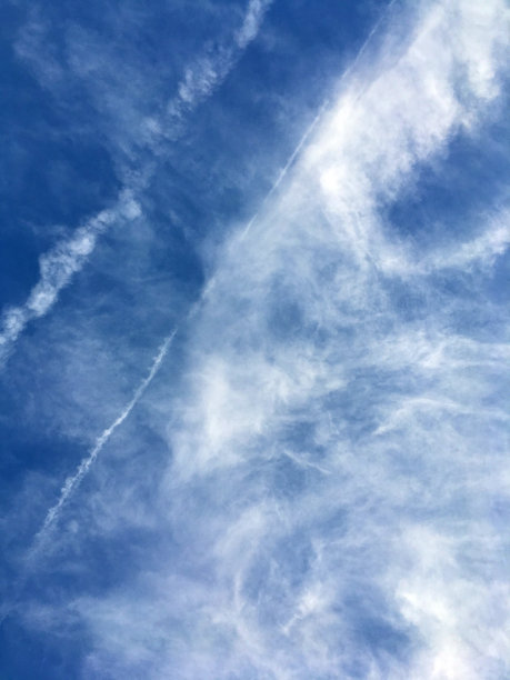 飞机的轨迹和明亮的蓝色天空中的一些云图片下载