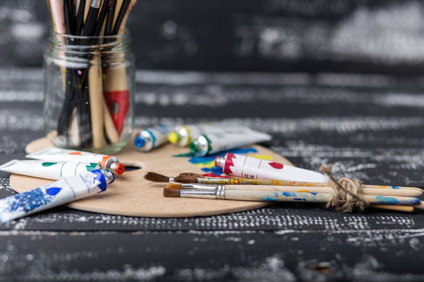 艺术家的工作室。俯视图的画笔调色板和丙烯酸颜料与白色帆布。一套画笔和油画颜料。艺术图片与复制空间和添加文本。儿童创造力项目图片下载