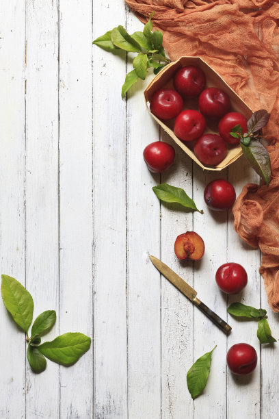 特写照片的新鲜红梅在一个篮子。俯视图上的白色复古木制背景。图片下载