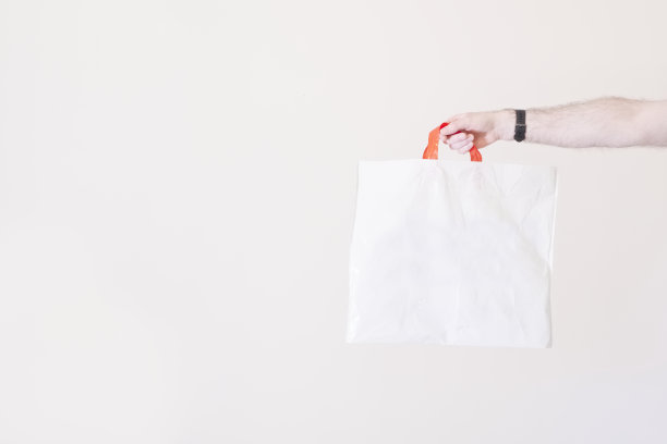空白塑料袋白色底面伸出一只手，手里拿着可回收的不可降解塑料图片下载