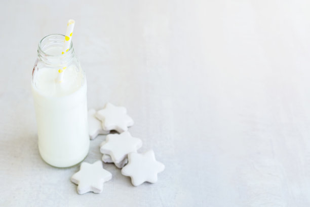 白色木桌上放着一瓶牛奶和星星饼干图片下载