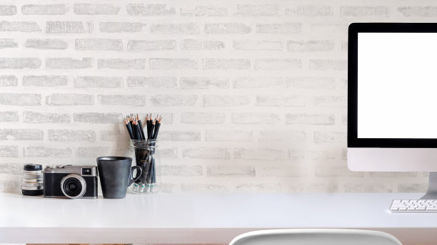 带办公用品的创意办公桌，白色砖墙。图片下载