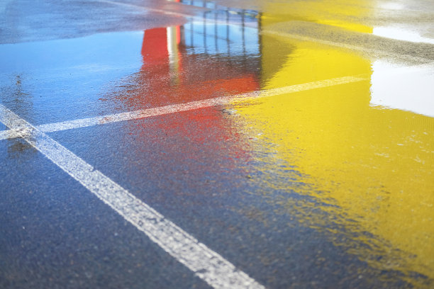 湿沥青上的反光。红色和黄色的斑点。白天。图片下载