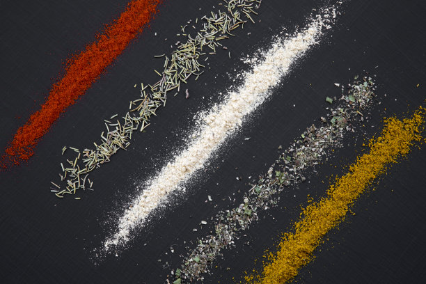 一组不同的香料和药草在一个黑色的背景，从上面看。图片下载