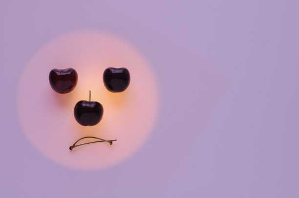 红色的樱桃水果放在橘黄色的圆圈里设为无聊的情绪脸图片下载