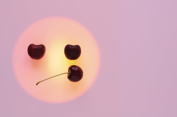 红色的樱桃水果放在橘黄色的圆圈里设为无聊的情绪脸图片下载