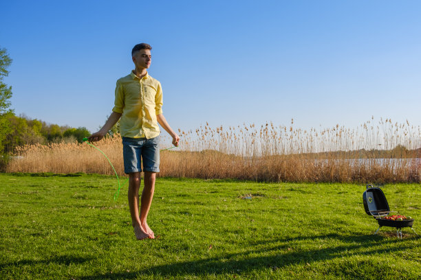年轻的白人男孩正在绿色的草地上跳绳锻炼图片下载
