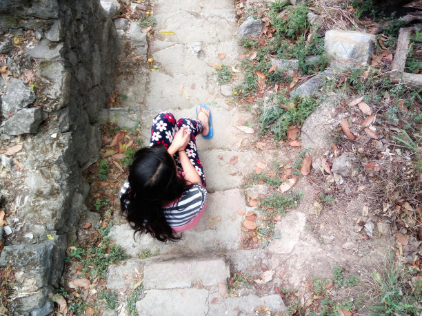 年轻的女孩坐在石头台阶上，感到悲伤图片下载