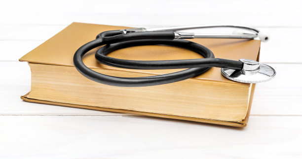 听诊器和书放在白色木桌上。关闭了。图片下载