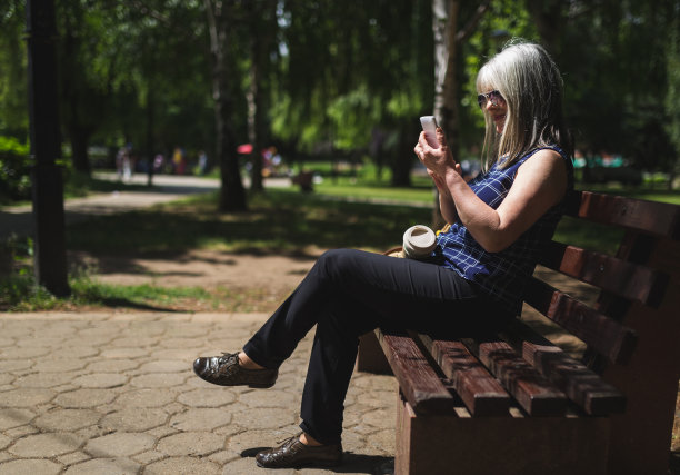 现代女性在公园里使用智能手机图片下载