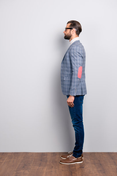 全身侧视图肖像聪明的绅士在高领，格子夹克，眼镜站在灰色的背景图片下载