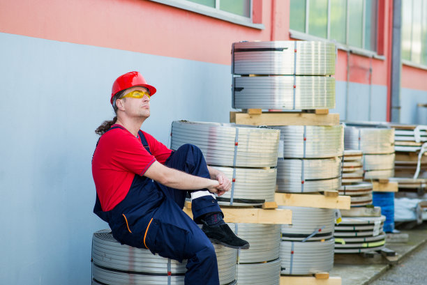 戴着红色头盔的工人在工厂外休息图片下载