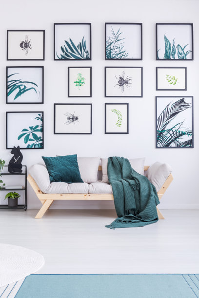 在一个简单的客厅里，一个沙发站在一堵满是植物画的墙旁边的真实照片图片下载