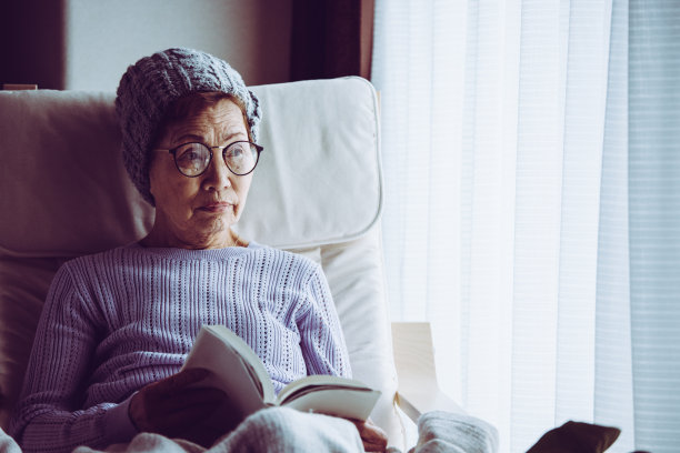 老妇人坐在窗边的椅子上看书图片下载