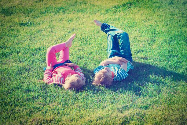 小男孩和小女孩在绿色的草地上休息图片下载