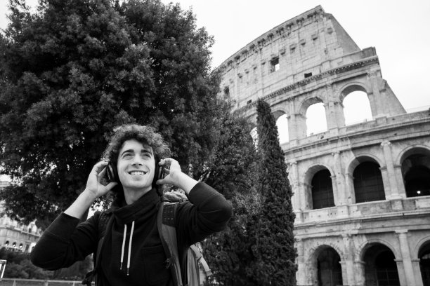 黑白图像英俊的年轻人戴着耳机在罗马斗牛场前听音乐图片下载