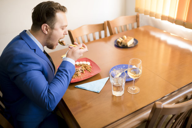 穿着蓝西装在家吃饭的商人图片下载