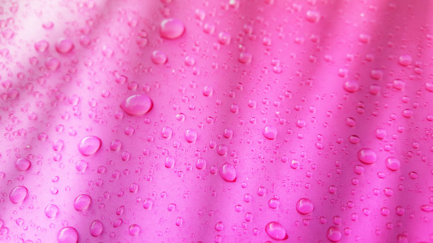 水滴背景在粉红色光滑的表面，雨滴在粉红色纹理上用于化妆品，饮料产品。图片下载