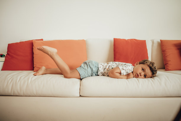 男孩躺在沙发上，看着写字板图片下载