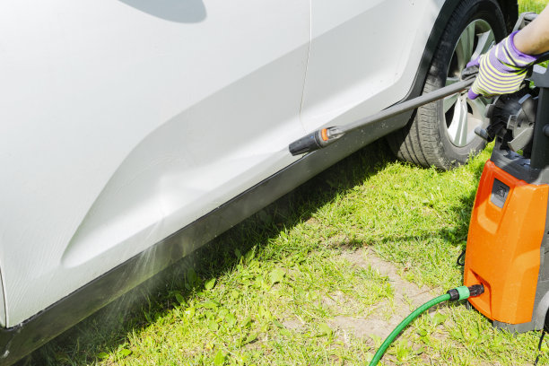 在洗车室外用加压水手动洗车。夏天洗车。使用高压水清洗汽车。汽车详细。手垫圈。图片下载