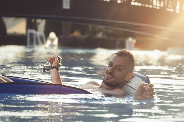 夕阳下的游泳池里，一个年轻人戴着泳镜微笑着图片下载
