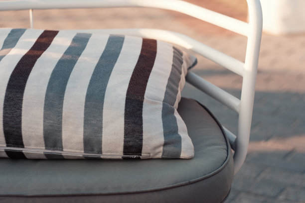 日落时海滩边的舒适枕头的放松椅的特写图片下载