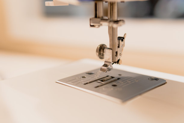 一个白色缝纫机脚的特写在模糊的背景。图片下载